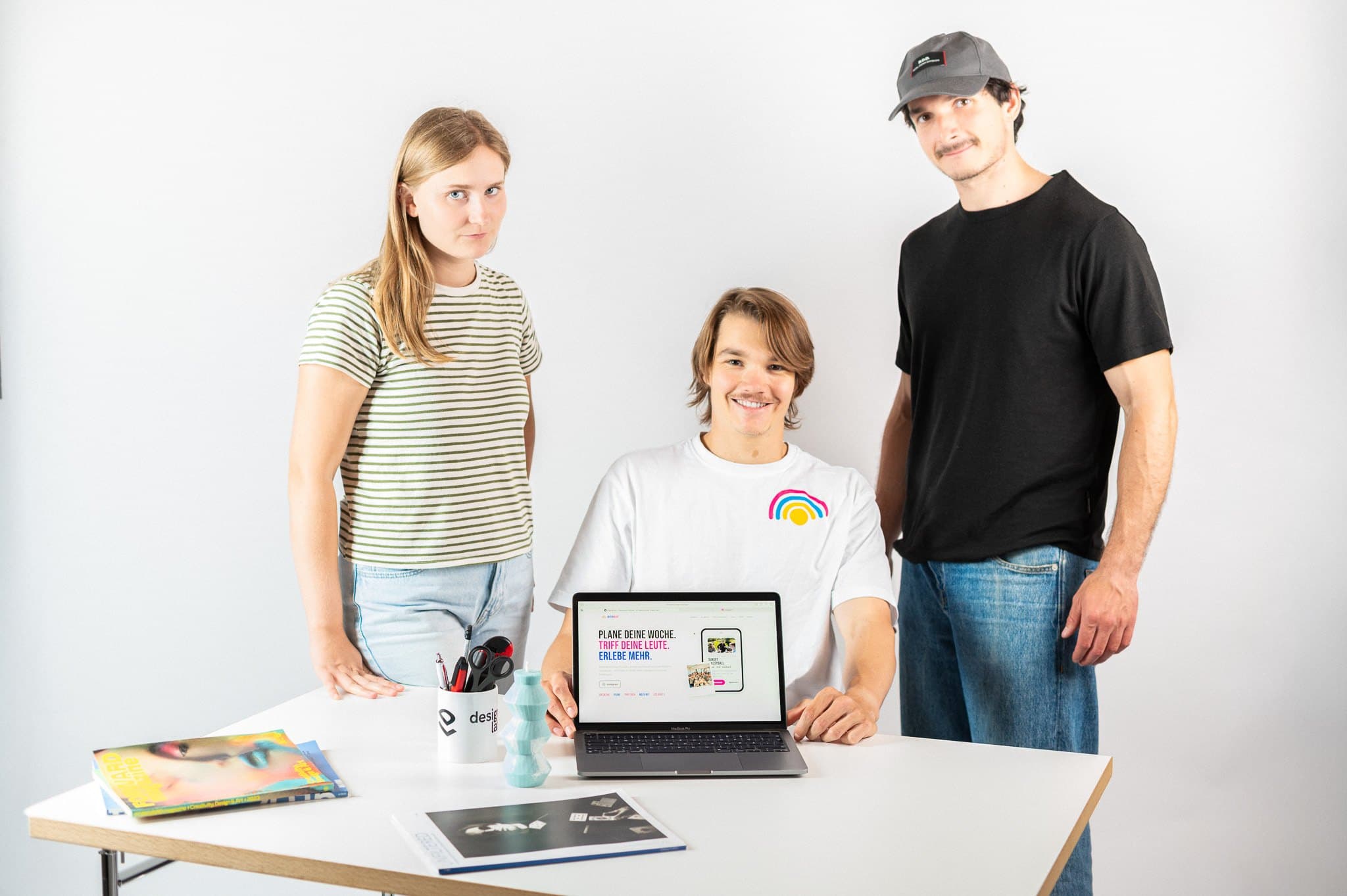 Drei Menschen stehen um einen Tisch mit Laptop